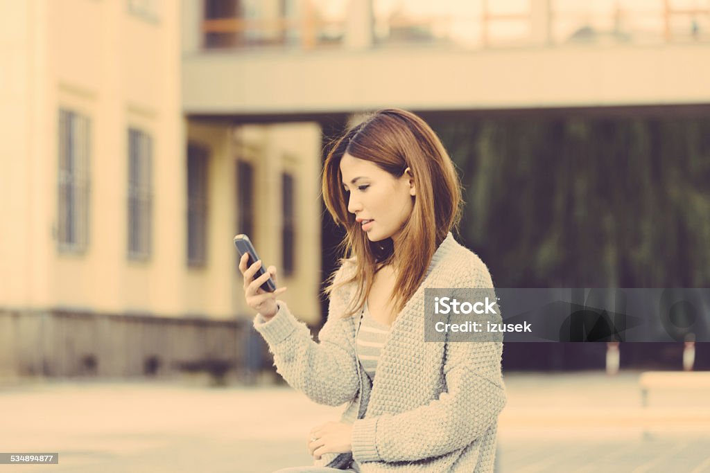 Asian woman using smart phones outdoor Outdoor portrait of asian young woman using smart phones. 2015 Stock Photo