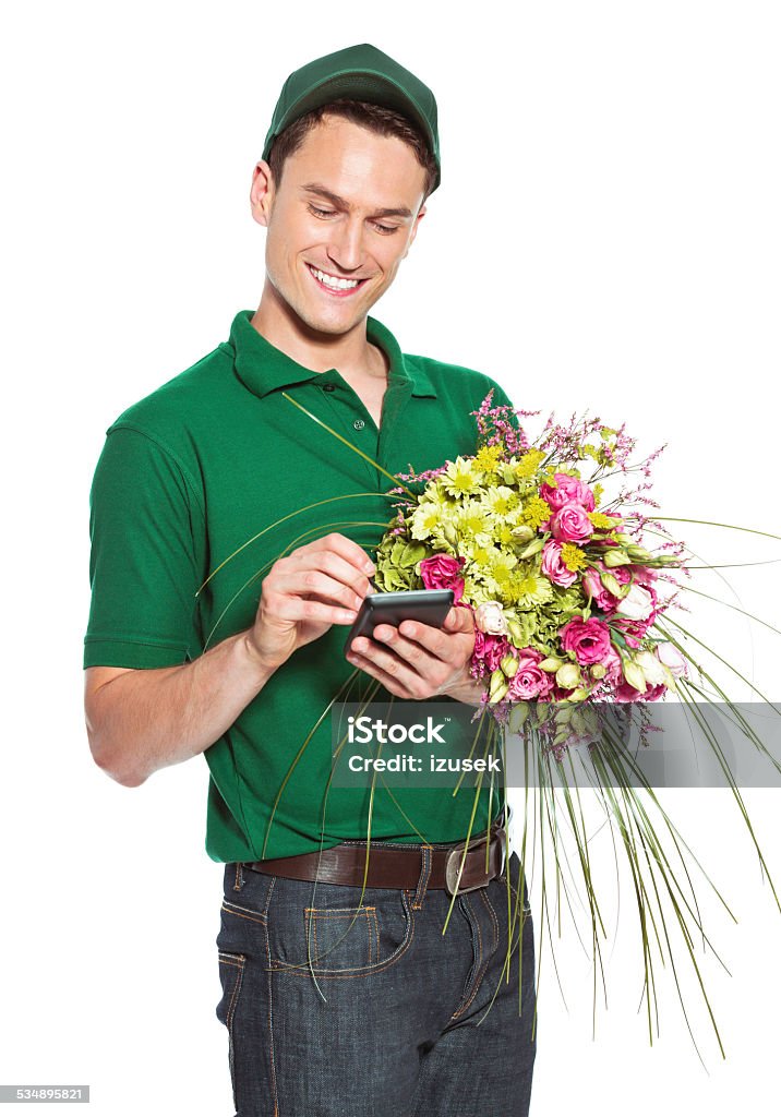 Delivery man with flowers Delivery man holding flowers and signing on palmtop. Studio shot, isolated on white. Delivering Stock Photo