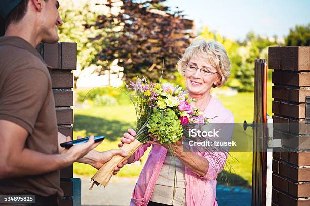 Delivery Man Delivering Flowers For Senior Woman Stock Photo - Download Image Now - Delivering, Bouquet, Yard - Grounds