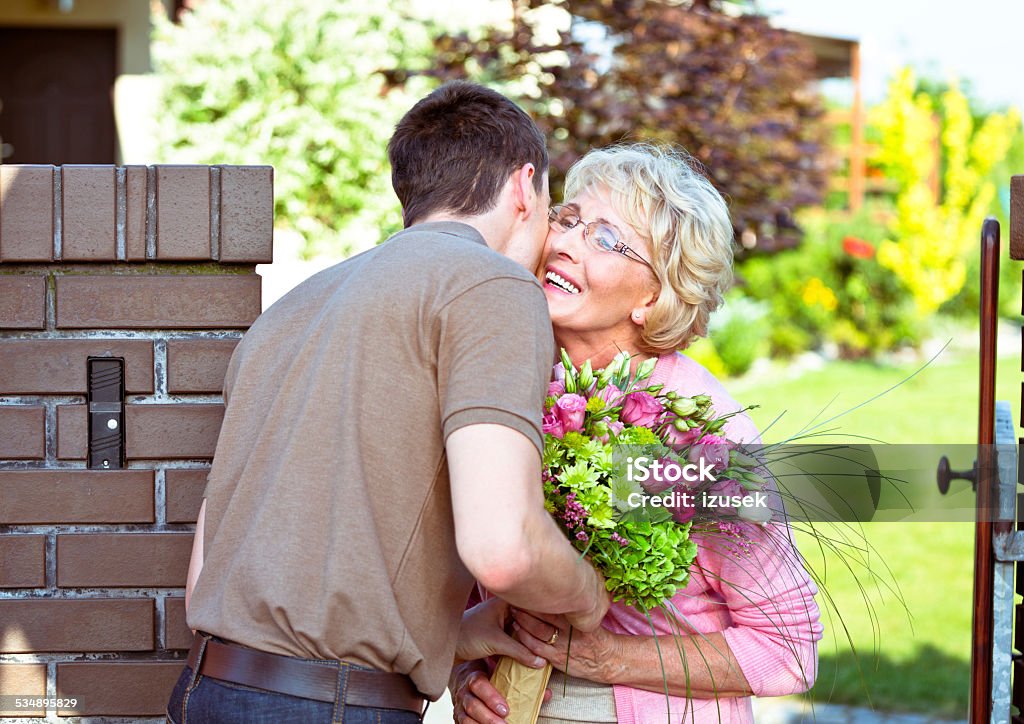 Grandson giving flowers to his grandmother Outdoor picture of grandson giving flowers to his happy grandmother. Mother Stock Photo