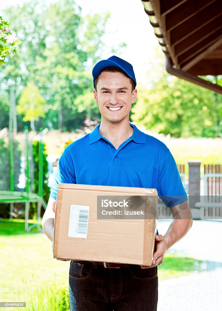 Courier delivering package Delivery man standing outdoor and carrying parcel, smiling at camera. Package Stock Photo