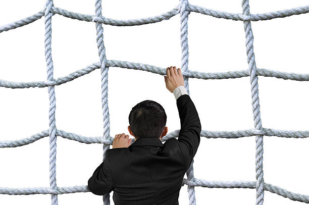 istock Businessman climbing crisscross rope net isolated on white 534895915