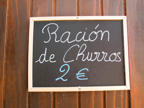 black placard spanish white handwritten in wall with typical menu food dishes like churros ration in Spain restaurant