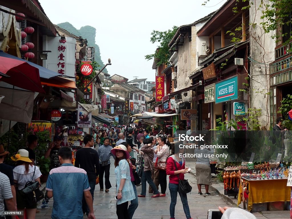 Tourists in Yangshuo, Guangxi China Yangshuo, China - April 28, 2014: Crowd of chinese tourists on the streets of Yangshuo, a popular village famous for its beautiful location, surrounded by karst limestone hills in South China., Guangxi Region 2015 Stock Photo