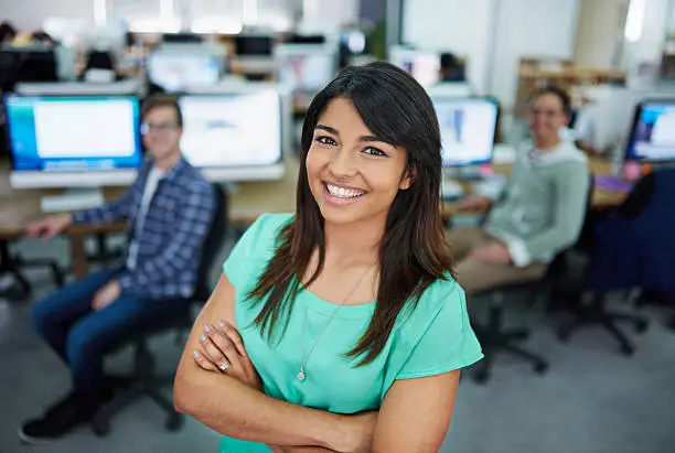 Portrait of a young woman standing in an office with designers in the backgroundhttp://195.154.178.81/DATA/shoots/ic_784886.jpg