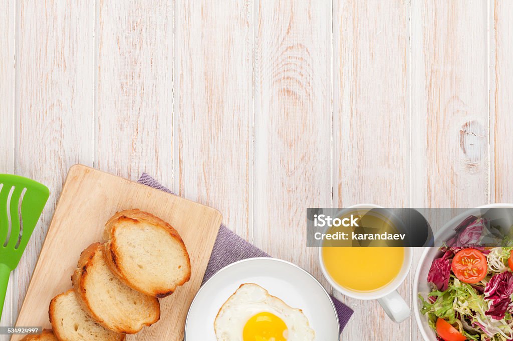 Healthy breakfast with fried egg, toasts and salad Healthy breakfast with fried egg, toasts and salad on white wooden table with copy space 2015 Stock Photo