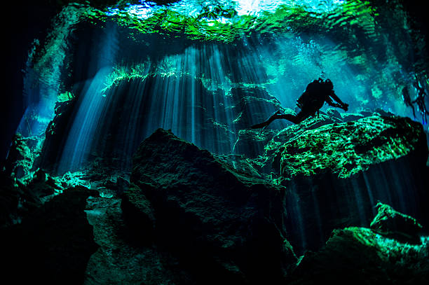 Scuba diver in underwater caves Scuba diver exploring the underwater cenotes in Mexico near Puerto Aventuras. Caves are dark and the light always gives different amazing ambient underwater. puerto aventuras stock pictures, royalty-free photos & images