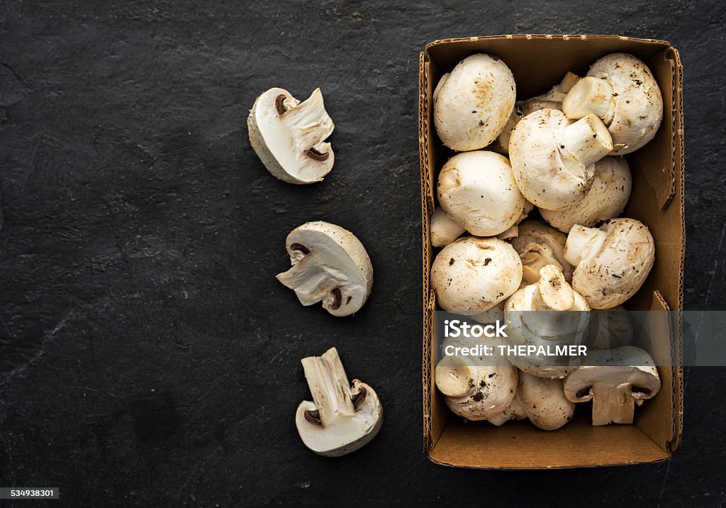 White button mushrooms White button mushrooms on a paper container - all set on a stone slate. 2015 Stock Photo