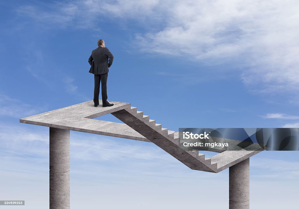 Businessman and Impossible Staircase Rear view of businessman standing and looking on the impossible staircase with cloudy sky background. He is looking further, thinking and searching new ideas. Digitally generated image inspired Escher's impossible stairs. Illusion Stock Photo