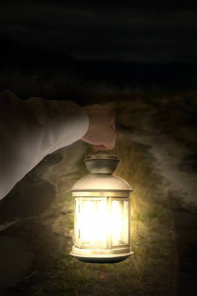 istock Left hand holding light illuminating dark road at night 534939255