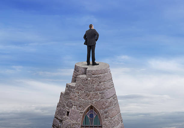 Businessman on the Tower Rear view of businessman standing and looking on top of the tower with cloudy sky background. He is looking further, thinking and searching new ideas. Digitally generated image. tower of babel stock pictures, royalty-free photos & images