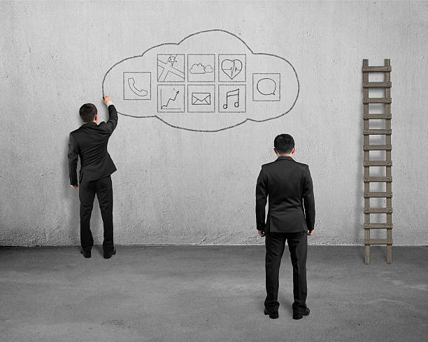 istock Manager looking at businessman drawing app icon on concrete wall 534940849