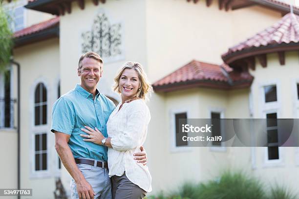 Mature Couple Standing In Front Of Their Mansion Stock Photo - Download Image Now - Couple - Relationship, House, In Front Of