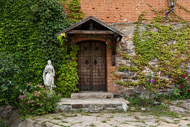 Cozy small rural white house with a wooden front door and green leaves on the left