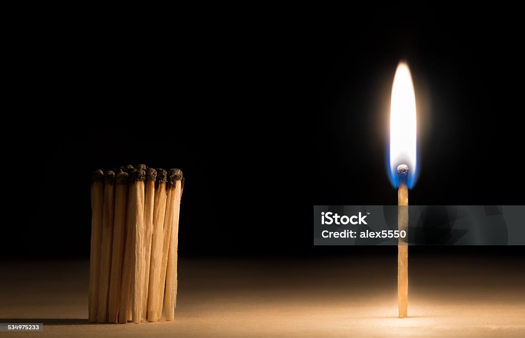 Crowd of burnt  matches standing before match on fire concept Crowd of burnt  matches standing before match on fire concept of motivation leadership on black 2015 Stock Photo