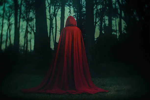 Red caped character from behind in the woods.