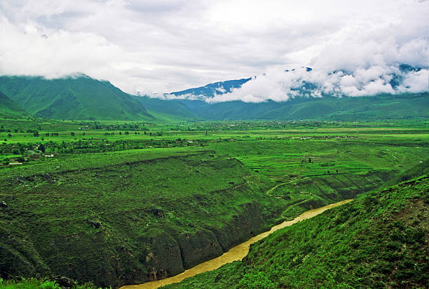 chinese landscape in yunnan province - deep river canyou, lush green fields and mountains enshrouded with mist