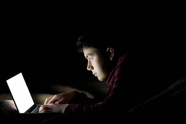 istock Teen using laptop in bed late at night 535011143