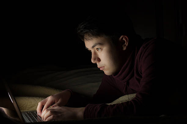 istock Teen using laptop in bed late at night 535011145