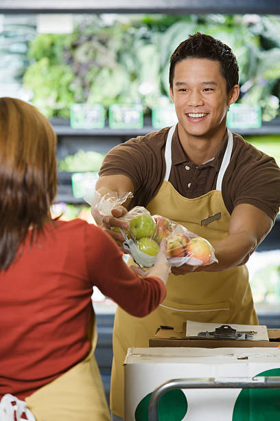 セールス担当アシスタント処理パケットのりんご - supermarket sales clerk grocer apron ストックフォトと画像