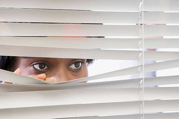 mujer mirando a través de las persianas - surveillance human eye security privacy fotografías e imágenes de stock