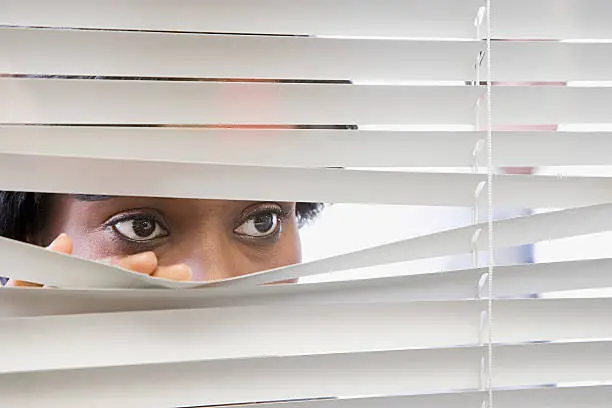 Photo of Woman looking through blinds