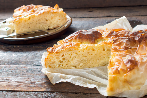 Selective focus on the sliced front cheese pie called burek on wooden background