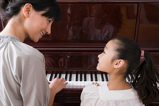 A mother and daughter playing the piano