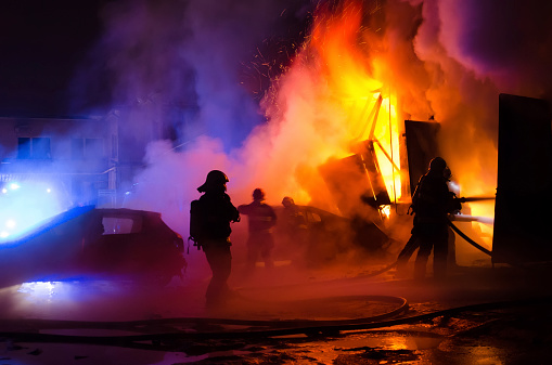 A closeup of Firefighters on the stairs extinguish a big fire