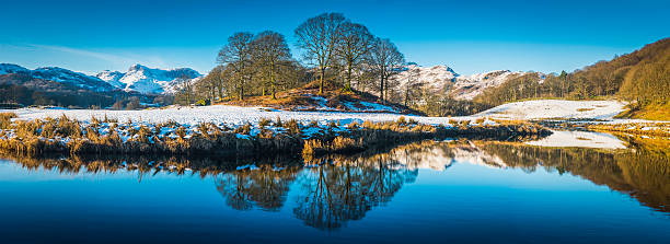 tranquillo lago blu riflettendo snowy mountains stand di alberi panorama - langdale pikes panoramic english lake district cumbria foto e immagini stock