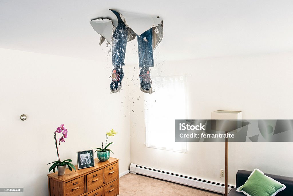 Man breaks ceiling drywall while doing DIY Man breaks ceiling drywall while doing home improvements. Humor Stock Photo
