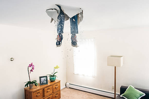 Man breaks ceiling drywall while doing DIY Man breaks ceiling drywall while doing home improvements. conceptual realism stock pictures, royalty-free photos & images