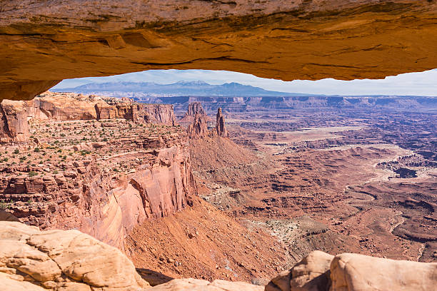 Canyonlands National Park. Mesa Arch, canyons and La Sal Mountains United States. Utah. Canyonlands National Park. Mesa Arch frames a scenic canyon vista with La Sal Mountains in the background. Mesa Arch is a pothole arch formed by surface water. To form a pothole arch, the water collects in some natural depressions and erodes soft layers below. la sal mountains stock pictures, royalty-free photos & images