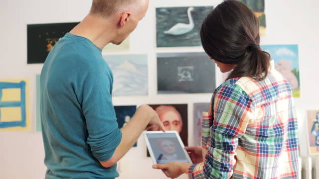 Artists discussing about a painting image using a digital tablet.
