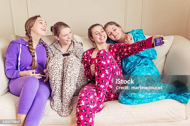 Girlfriends Wearing Onesies Chilling On A Couch With Mobile Phones Stock Photo - Download Image Now