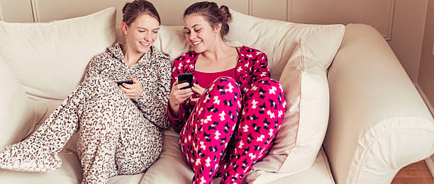 istock Girlfriends wearing onesies chilling on a couch with mobile phones. 535070855