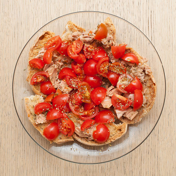 Dried bread called freselle with tuna and tomatoes on wooden table