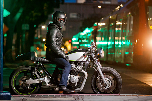 Man on custom built motorcycle at night in an urban scene. Shallow depth of field.