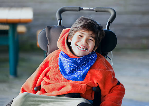 Handsome, happy biracial eight year old boy smiling in wheelchair stock photo