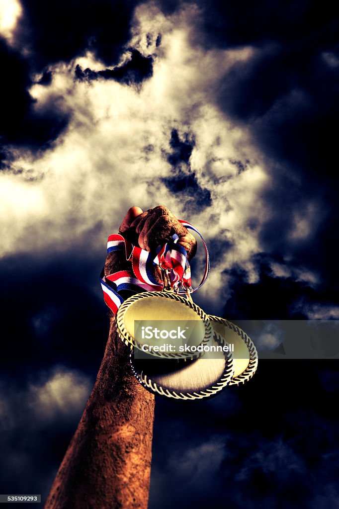 American Victory with Trophy Medallion and Muddy Arm This is a photo of a athlete holding his muddy arm into the air in victory with medals after a game. International Multi-Sport Event Stock Photo