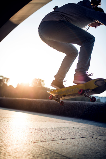 Skater girl flipping a skateboard. Backlit shot.
