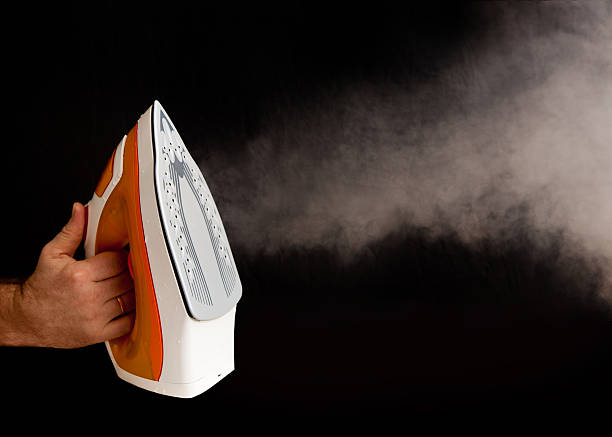istock Man's hand with orange iron on black background 535110813
