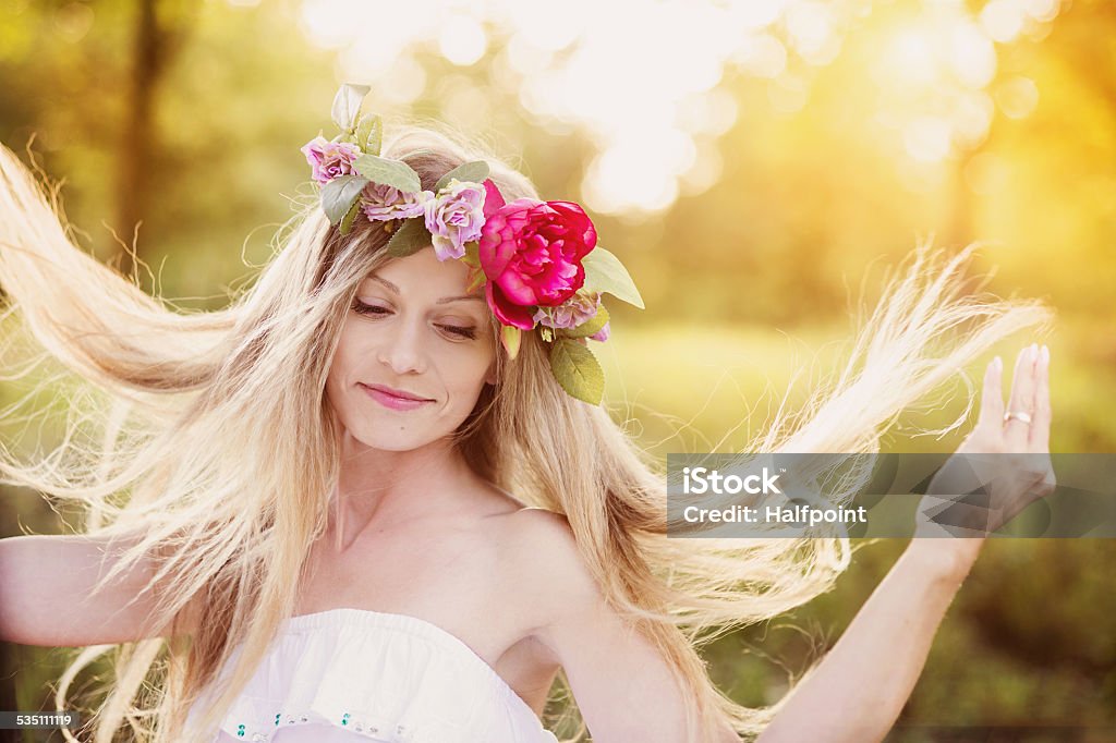 Beautiful woman with flower wreath. Attractive young woman with flower wreath on her head with sunset in background. 2015 Stock Photo