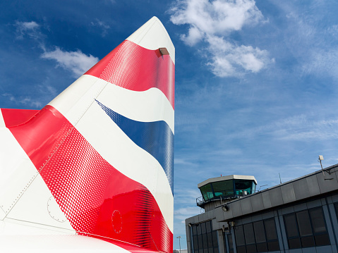 London, UK - August 28, 2014: The tail of a British Airways airplane with the tower of London City Airport