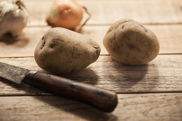 istock Raw potatoes with rustic kitchen knife on wooden table 535112477