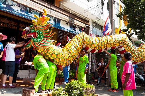 Bangkok, Thailand - February 8, 2014: Thai people are giving money to chinese dragon. Some Thai men are doing dragon dance and parade during Mae Kuan-Im procession in street Chokchai 4. Buddhist procession and event.