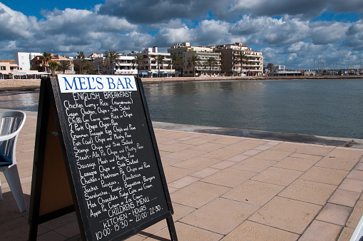 Cala Estancia, Majorca, Spain - February 12, 2013: Sunday breakfast at Mel's Bar with a view towards the small hotels across the bay from the pier.