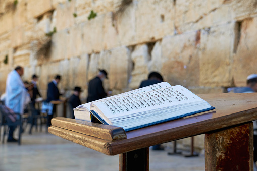 Jerusalem, Israel - January 30, 2015: Western Wall also known as Wailing Wall in Jerusalem. People are praying. The Torah Book in the foreground.