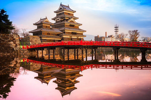 Matsumoto, Japan - November 20, 2014: Typical red bridge and Matsumoto Castle, also known as Crow Castle because of it\\'s mostly black exterior, was built in the early 16th century.