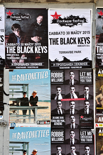 Athens, Greece - January 16, 2015: City wall covered with concert posters for upcoming live music shows by The Black Keys, Raveonettes and Robbie Williams.